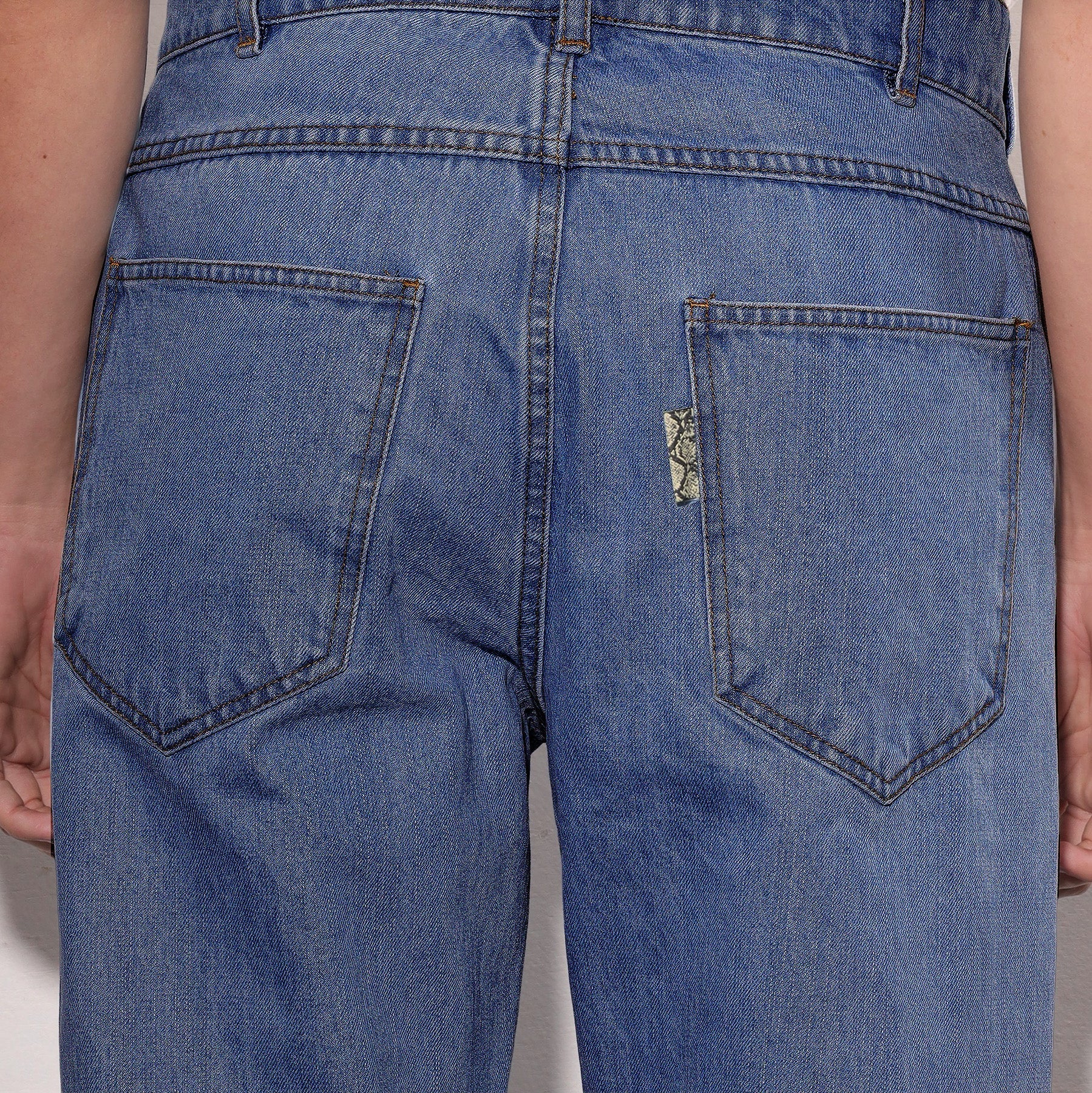 Close-up of blue jeans with a brand logo on a plain background